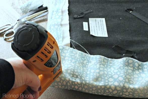 woman reupholstering an office chair with a staple gun.