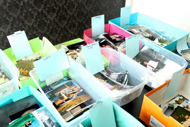 boxes of sorted paper photos on top of card tables.