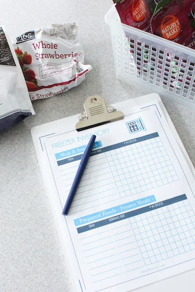 kitchen countertop with printable freezer inventory on clipboard next to freezer items