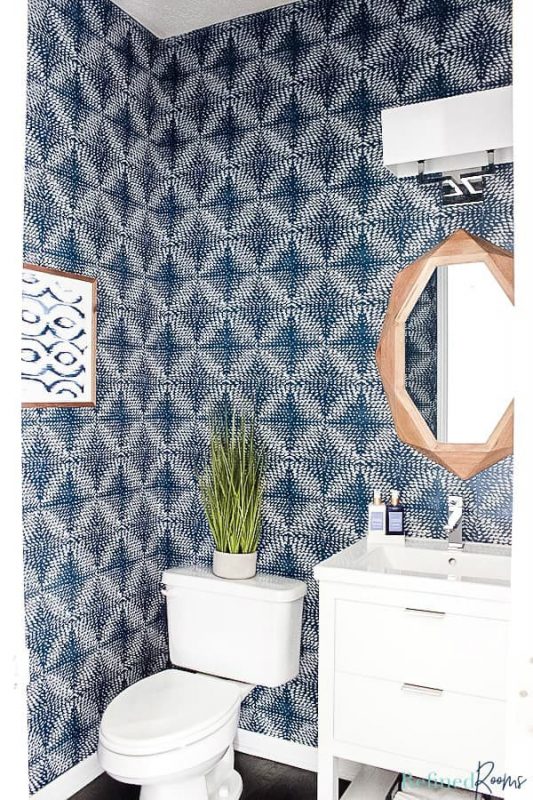 vertical shot of redesigned blue and white coastal powder room - toilet, vanity, mirror and light.