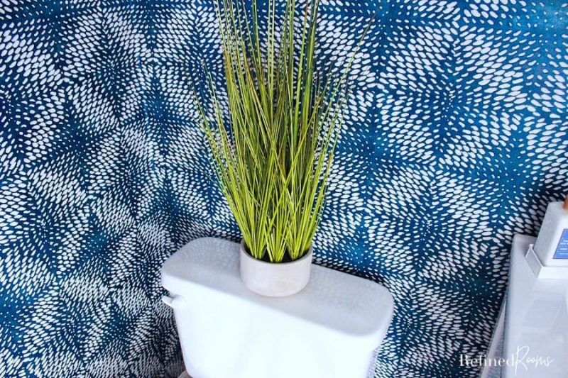 decorative faux grass in cement container on top of toilet.