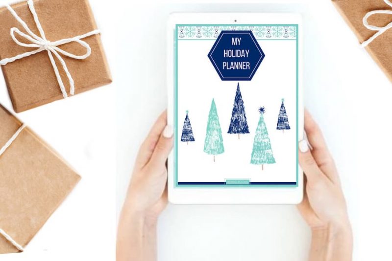 desktop with woman's hands holding tablet displaying digital holiday planner.