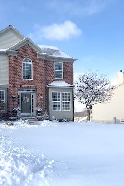 house with snow in front yard and SOLD real estate sign.